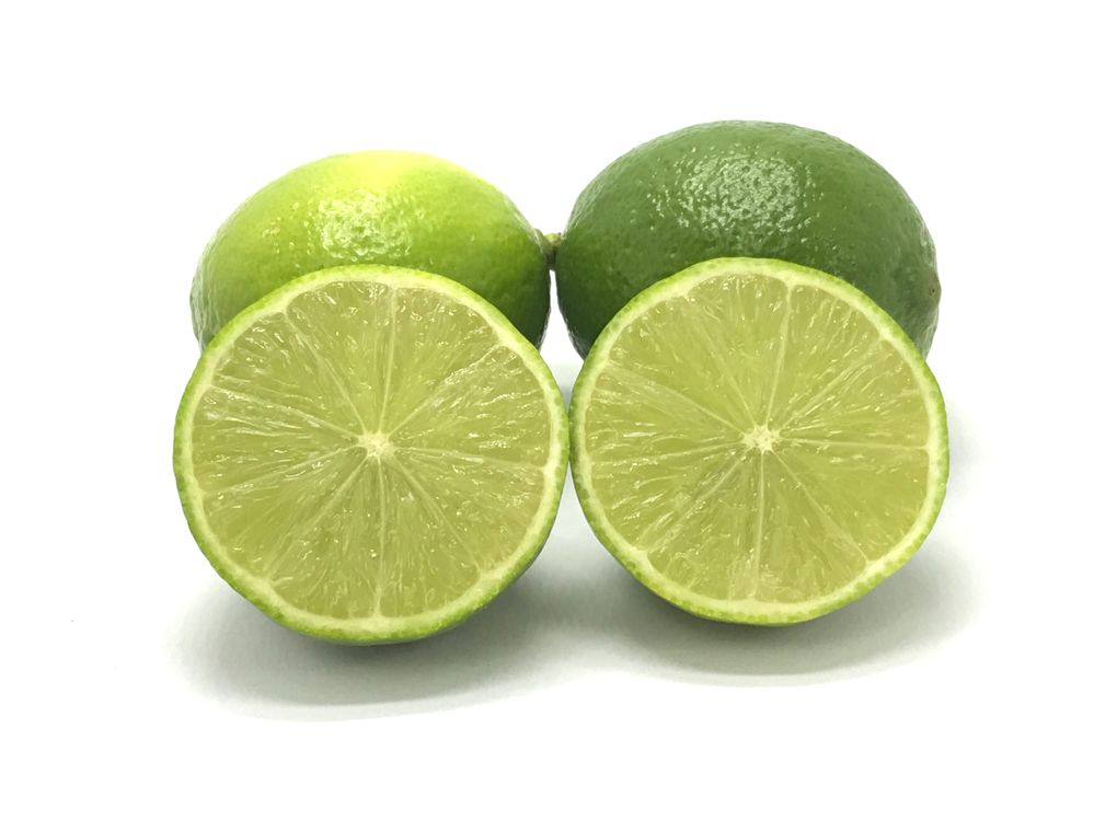 Two green Tahiti lemons from Brazil and two slices on white background..jpg