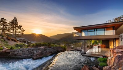 Firefly Modern looking Frank lloyd wright style house overhanging a running stream with mountains in.jpg