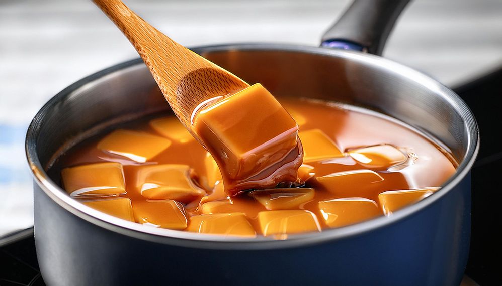 Firefly caramel fudge cooking in pot on stove being stirred with a wooden spoon, with light reflecti.jpg